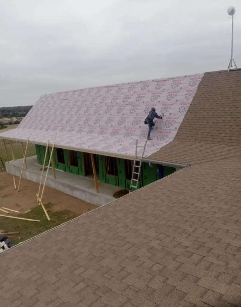 Worker preparing underlayment for a metal roof installation in North Royalton